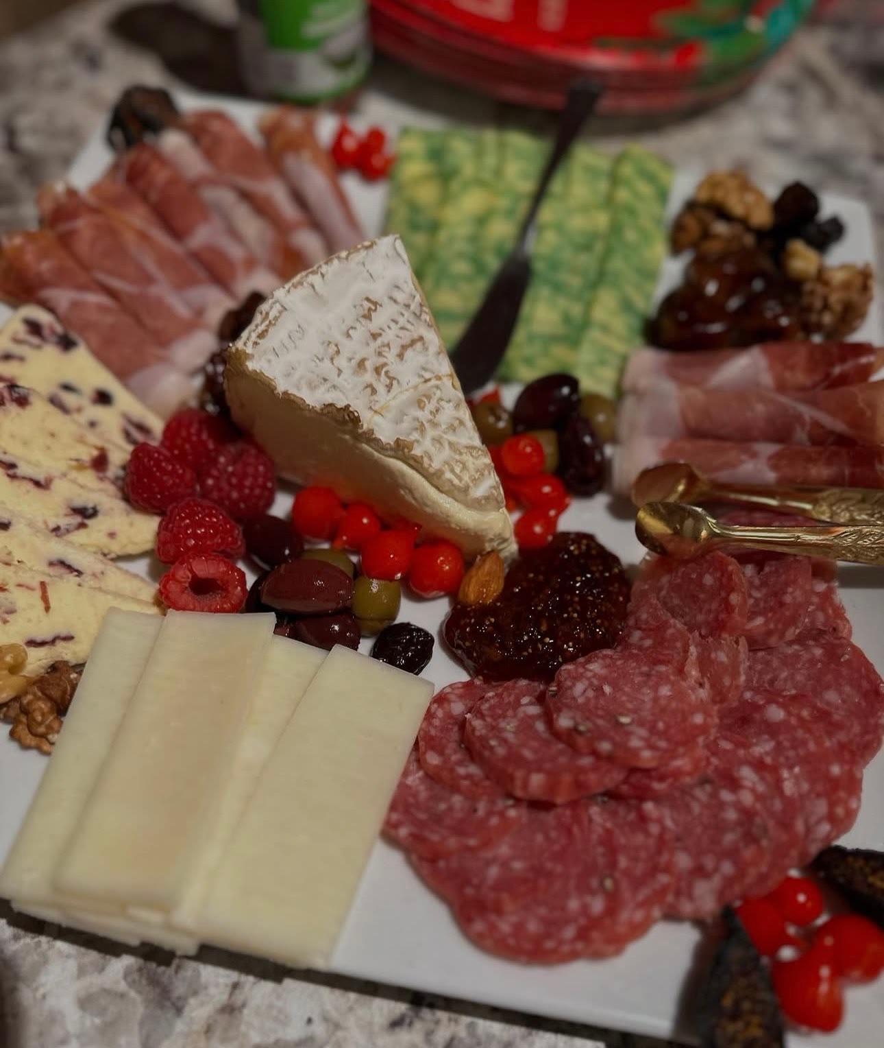 A board of cured meats, cheeses, berries, nuts and dried fruit