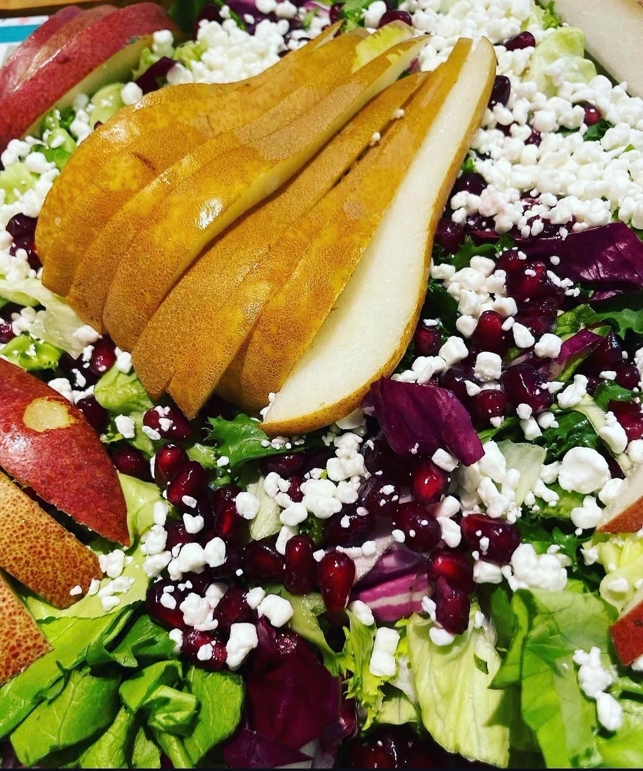 Salad with sliced pears, pomegranate seeds, crumbled white cheese and radicchio