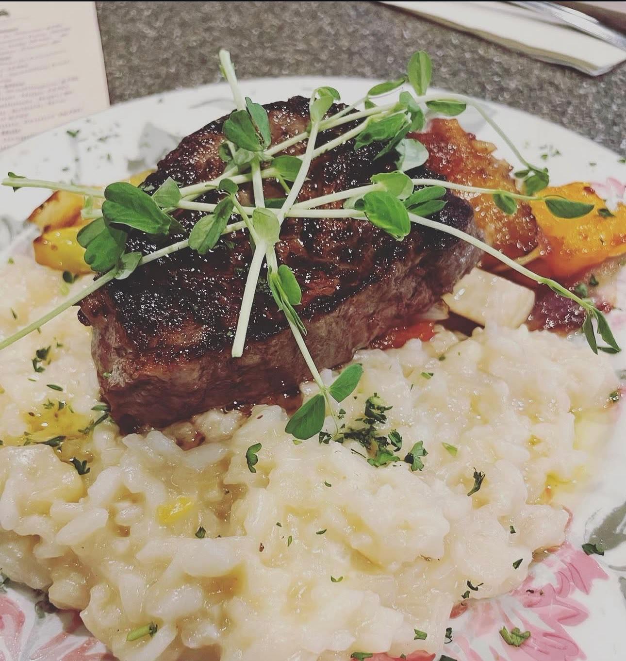 Seared steak over creamy risotto topped with microgreens